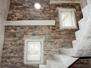 Neu renoviertes Treppenhaus im Projekt Artist for Kids mit freigelegtem Sichtmauerwerk und Treppenaufgang mit Sichtbeton
